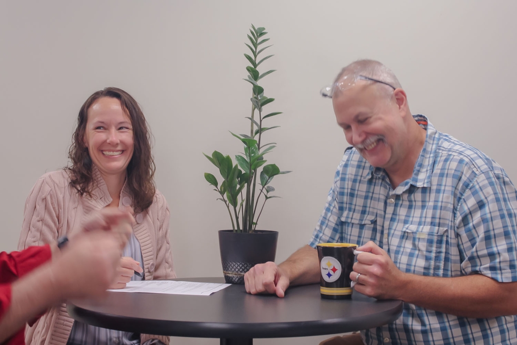 employees laughing at table with coffee